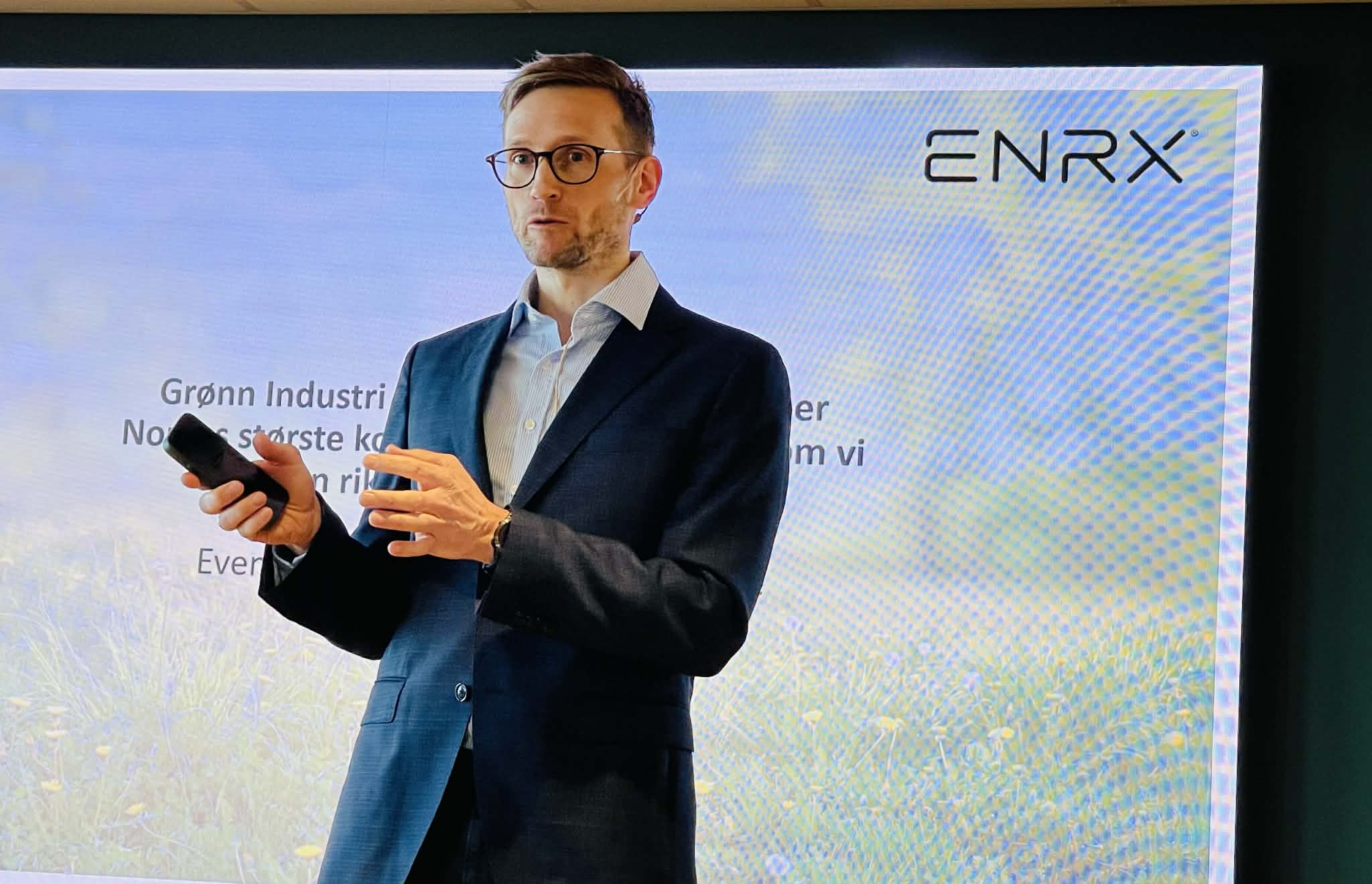 Foredragsholder i dress står foran presentasjonsskjerm med ENRX-logo og tekst om grønn industri.